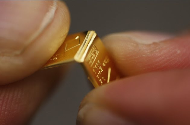 An employee shows dividing a gold Combibar at a plant of gold refiner and bar manufacturer Valcambi SA in the southern Swiss town of Balerna