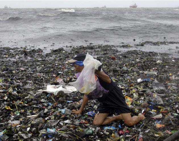 An old woman crawls on top of floating debris washed ashore due to Typhoon Nanmadol as she looks for salvagable materials Saturday, Aug. 27, 2011 in Manila, Philippines. Forecasters said the typhoon h