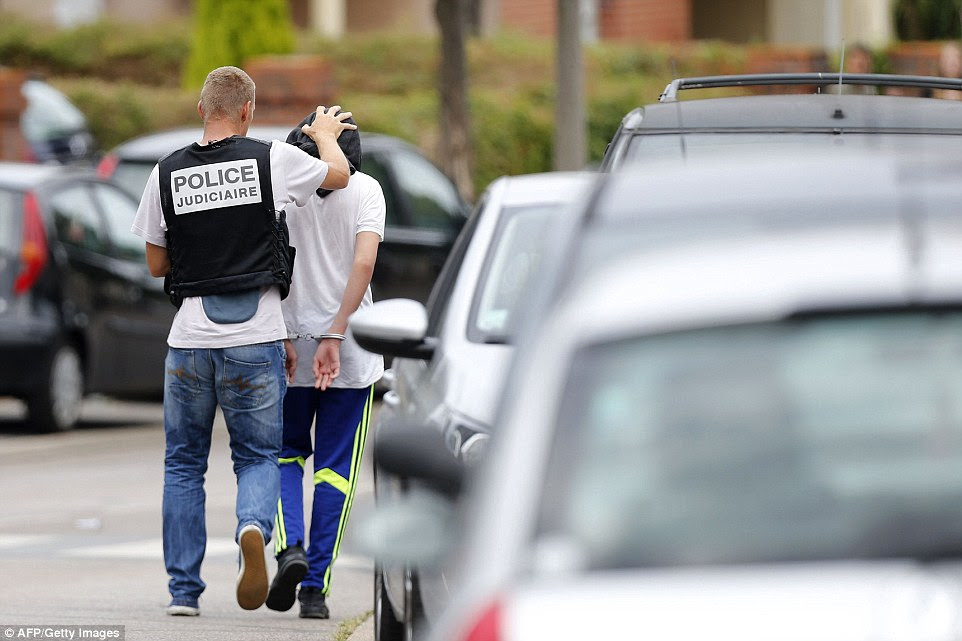 Um policial francesa prende um homem após uma busca em uma casa na cidade de Normandy de Saint-Etienne-du-Rouvra. Ele veio depois de um sacerdote foi massacrado em uma igreja na cidade