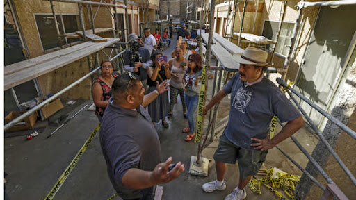 Gilbert Nunez, left, owner, of sandblasting company, talks to John Urquiza and other residents of a Highland Park apartment complex Marmion Royal, picketing to block workers from sandblasting their courtyard.