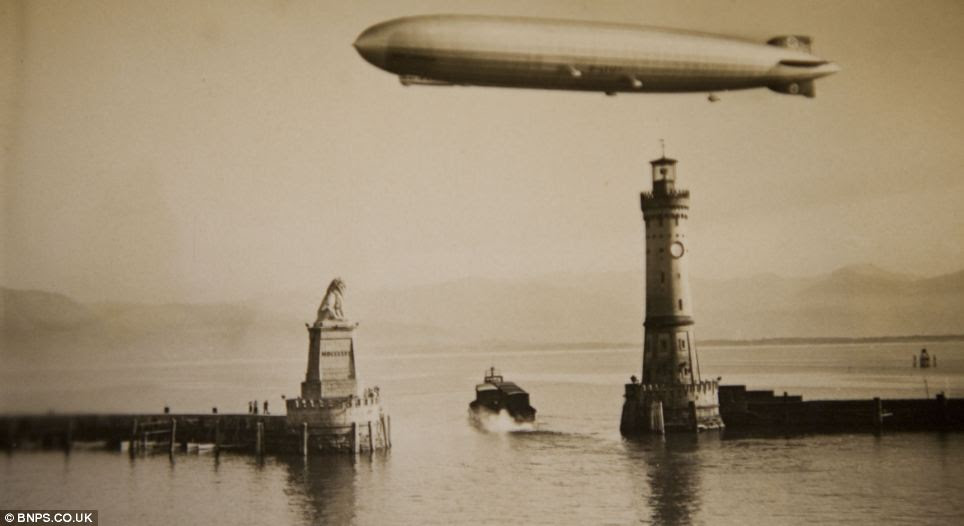 Reflected glory: A shining Zeppelin flies over calm waters at Lindau harbour in Bavaria in one of the amazing photographs