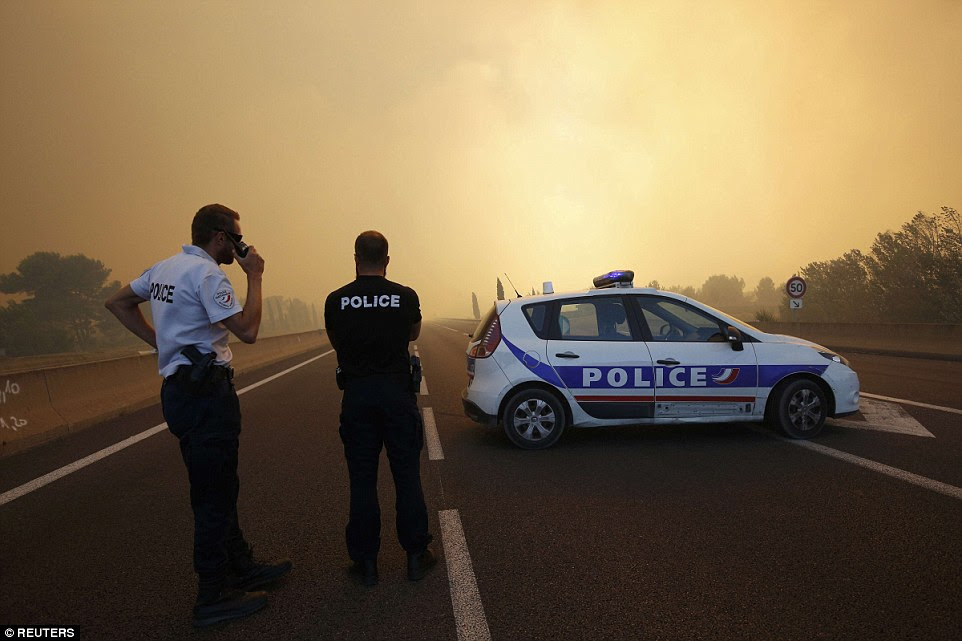 A polícia francesa diante de um obstáculo como o fumo enche o céu e bloqueia o sol como fogos queimam norte de Marselha