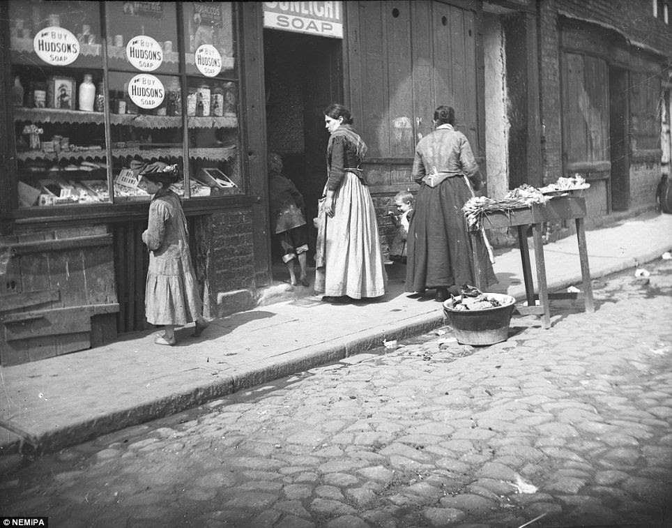 Scouting the wares: A young girl examines the window display of a city shop selling fresh veg, sunlight soap and sweets