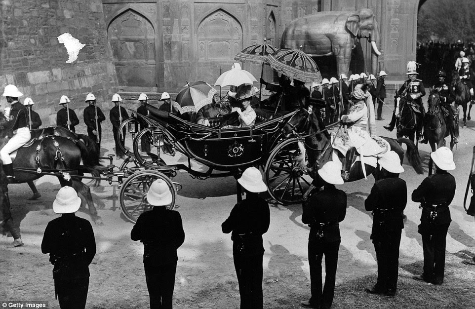 Queen Mary rides in an open top carriage past a guard of honour lining the street during her tour of the area 104 years ago