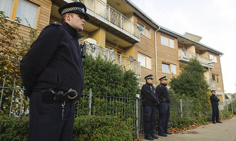 Police officers stand outside flats in Brixton