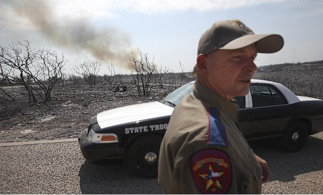 Texas State Trooper Garry Allen stands guard in an area destroyed by a wildfire at Possum Kingdom Lake, Texas, Wednesday, Aug. 31, 2011. (AP Photo/LM Otero)