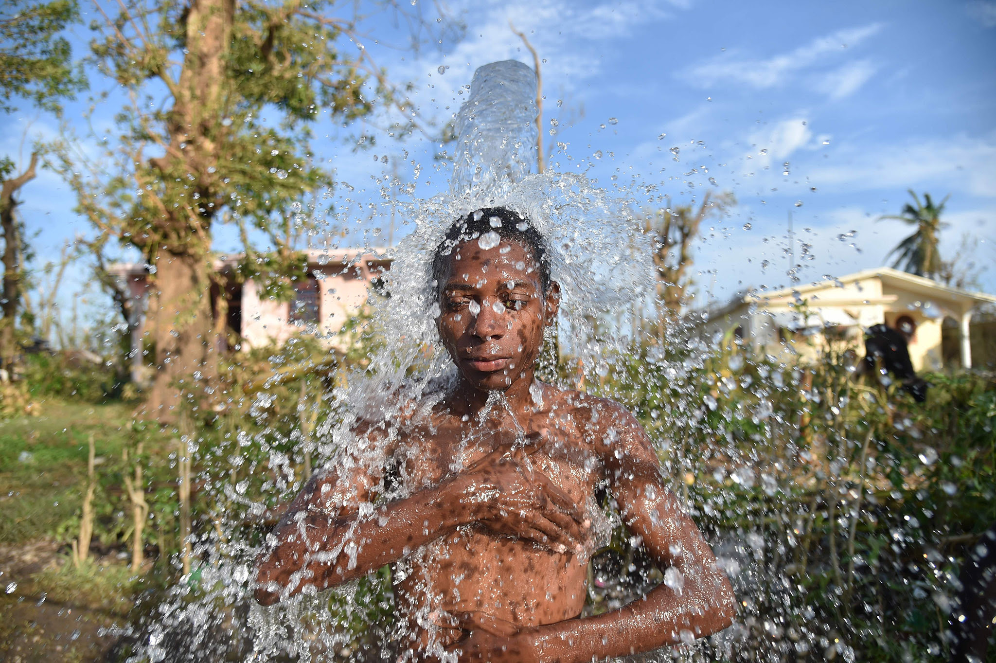 A young man takes a shower in a shower from a water fountain in Houk, in a rural zone of Les Cayes, an area damaged by Hurricane Matthew, in the Southwest of Haiti, on October 9, 2016.  Haiti began three days of mourning Sunday for hundreds killed in Hurricane Matthew as relief officials grappled with the unfolding devastation in the Caribbean country's hard-hit south. Matthew crashed ashore on Haiti's southern coast on October 4 as a monster Category 4 storm, packing 145 mile (230 kilometer) winds. Civil defense officials have put the death toll at 336, although some officials said it topped 400.   / AFP PHOTO / HECTOR RETAMALHECTOR RETAMAL/AFP/Getty Images