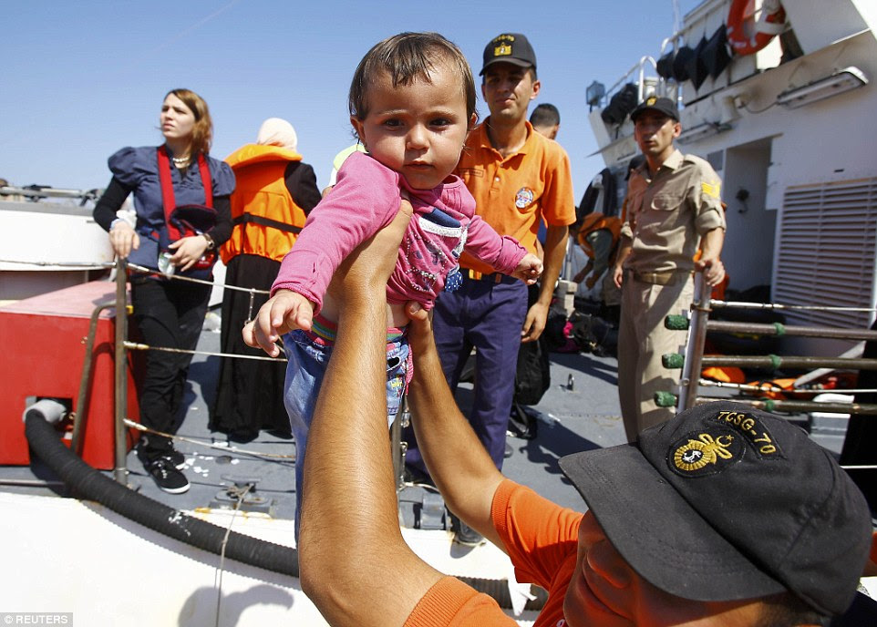 Lifted: A young Syrian migrant baby arrives in Cesme, near the Aegean port city of Izmir in Turkey