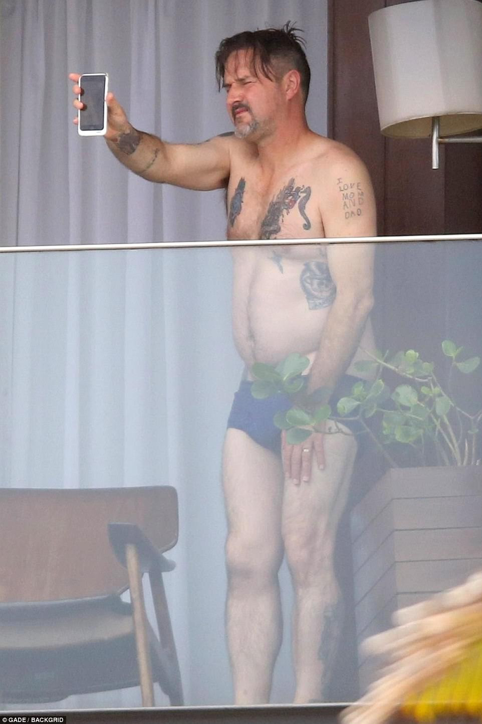 Fun in the sun: Actor David Arquette, 46, also looked relaxed as he seemed to enjoy a FaceTime session from his balcony at the luxury hotel