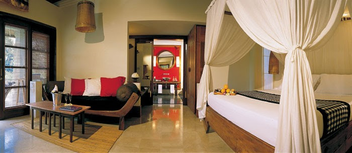 A canopied bed sits as a focal point in an open plan deluxe villa.
