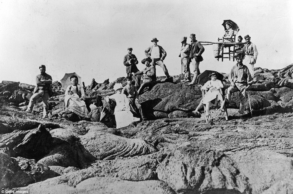 Local porters accompany Victorian tourists to the summit of Mount Vesuvius. One of them is being carried in an open, sedan type chair