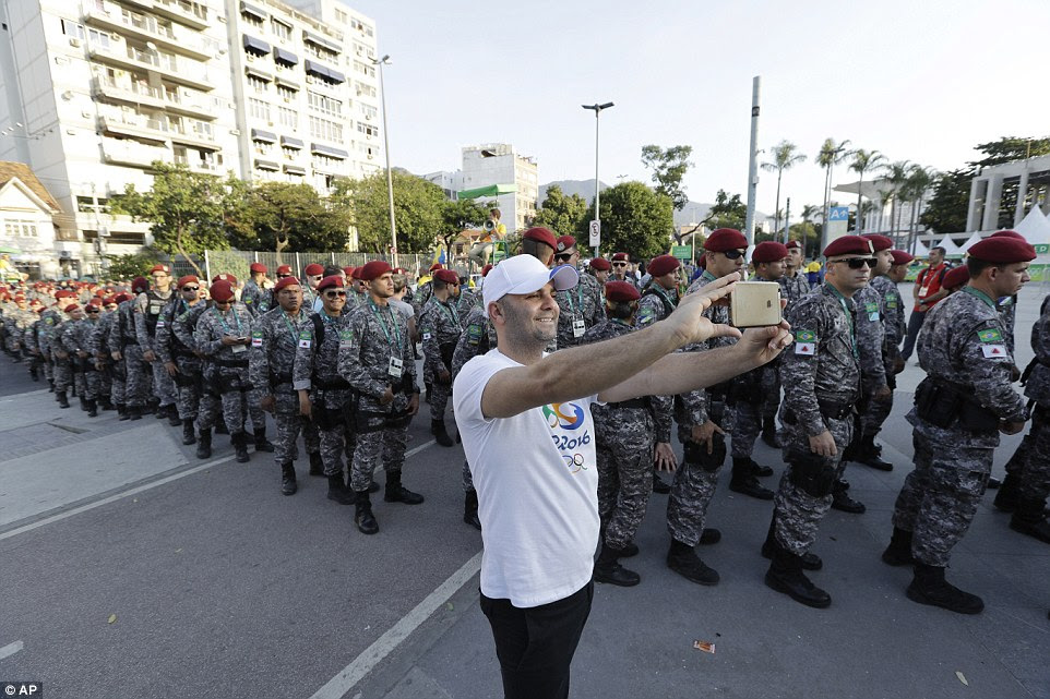 Estou com eles: Um fã de esportes furtivamente um selfie como colunas de soldados brasileiros montavam guarda fora do estádio do Maracanã