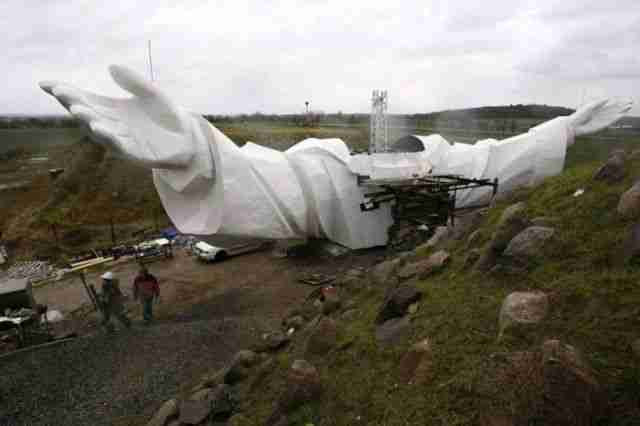 Workers walk near the arms of a statue of Jesus being built in Swiebodzin