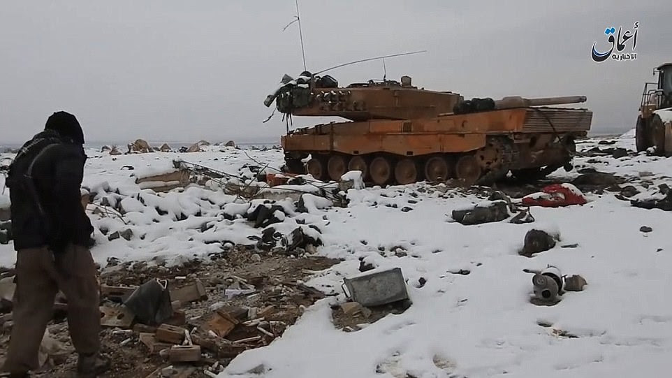A soldier examines the destroyed Leopard 2 with its broken turret as it sits stationary in the snow in northern Syria, surrounded by debris. It is believed to have been destroyed during Euphrates Shield 