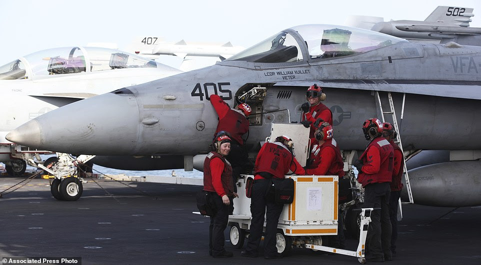 Crew members work on an F-18 fighter jet abroad the USS George H.W. Bush. The worry grows for U.S. officials as the Navy recorded 35 instances of what it describes as 'unsafe and/or unprofessional' interactions with Iranians forces in 2016