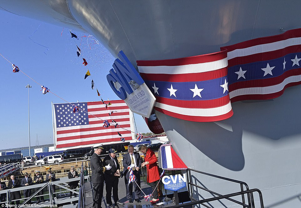 Susan Ford, who serves as the ship's sponsor, breaks a champagne bottle against a plate welded to the hull during a ceremony in 2013
