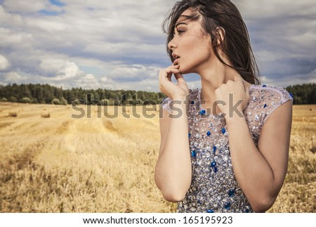 Young sensual & beauty woman in a fashionable white-blue dress pose on field.