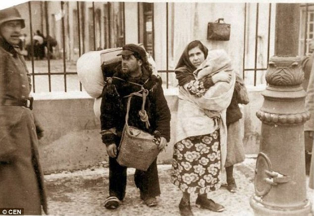 Death camps: A woman holds a child close to her chest alongside a man laden down with belongings as German troops herded residents into cattle trucks to deliver them to their deaths at Belzec