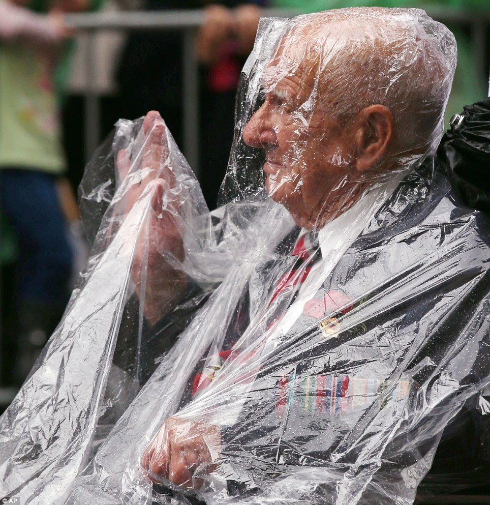 A war veteran uses a disposable rain coat to fend off the rain during the ANZAC Day parade in Sydney today