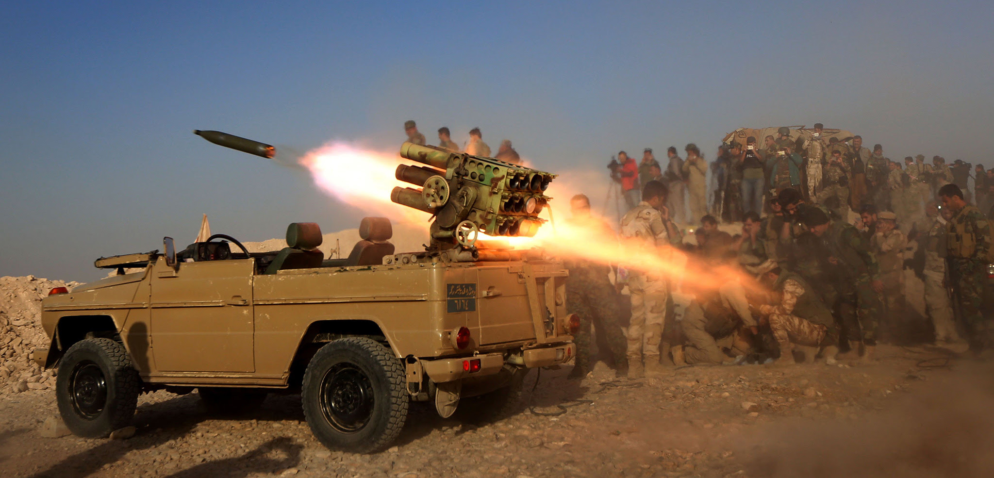 Iraqi Kurdish Peshmerga fighters fire a multiple rocket launcher from a position in Sheikh Ali village near the town of Bashiqa, some 25 kilometres north east of Mosul during an operation against Islamic State group jihadists to retake the main hub city.