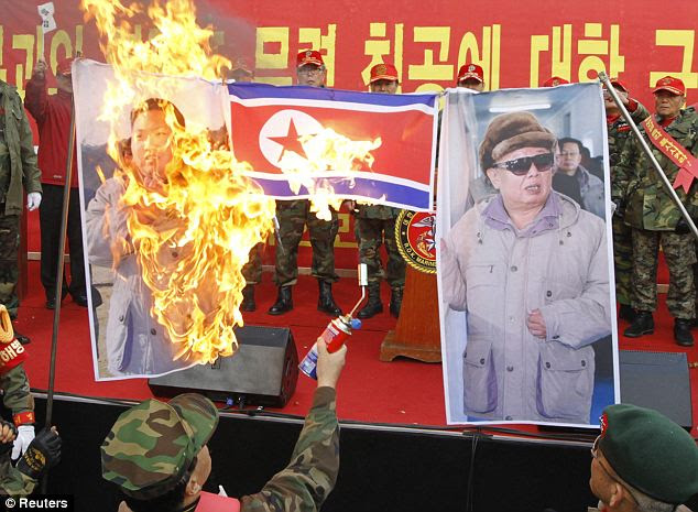 Retired South Korean Marines burn a North Korean flag and portraits of North Korean leader Kim Jong-il (R) and his son Kim Jong-un (L) 