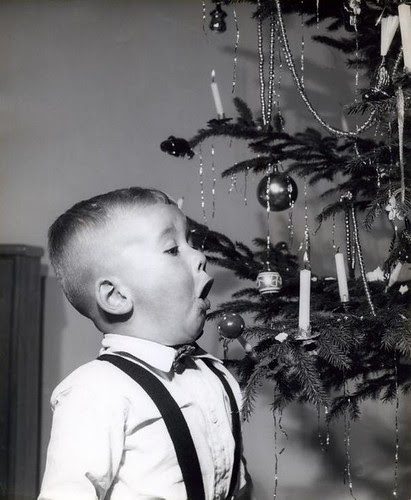 Jongen blaast kaars in kerstboom uit