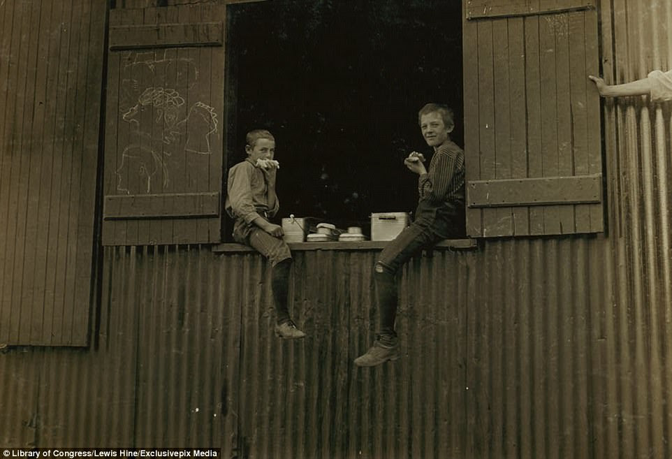 Two young boys dangled their legs over the side of a window as they tucked into sandwiches during their lunch break at Economy Glass Works in Morgantown, West Virginia. The photographer said there were many more child workers like this pair inside 