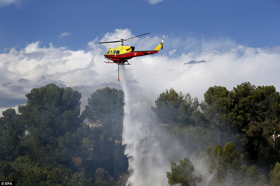 A firefighting helicopter drops water over a forest fire in Carros near Nice, southern France, as blazes broke out across the French Riviera