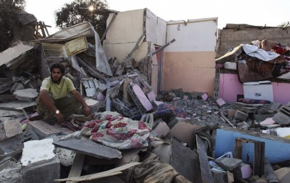 A Palestinian man sits on rubbles of a destroyed house after an Israeli air strike in Gaza