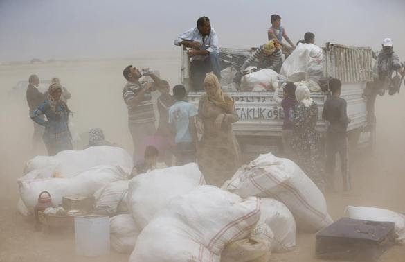 Kurdish Syrian refugees load their belongings on a truck during a sand storm on the Turkish-Syrian border near the southeastern town of Suruc in Sanliurfa province, September 24, 2014.  REUTERS-Murad Sezer