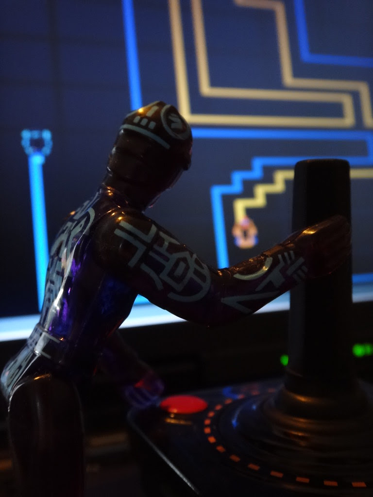 Tron action figure playing lightcycle video game with Atari joystick