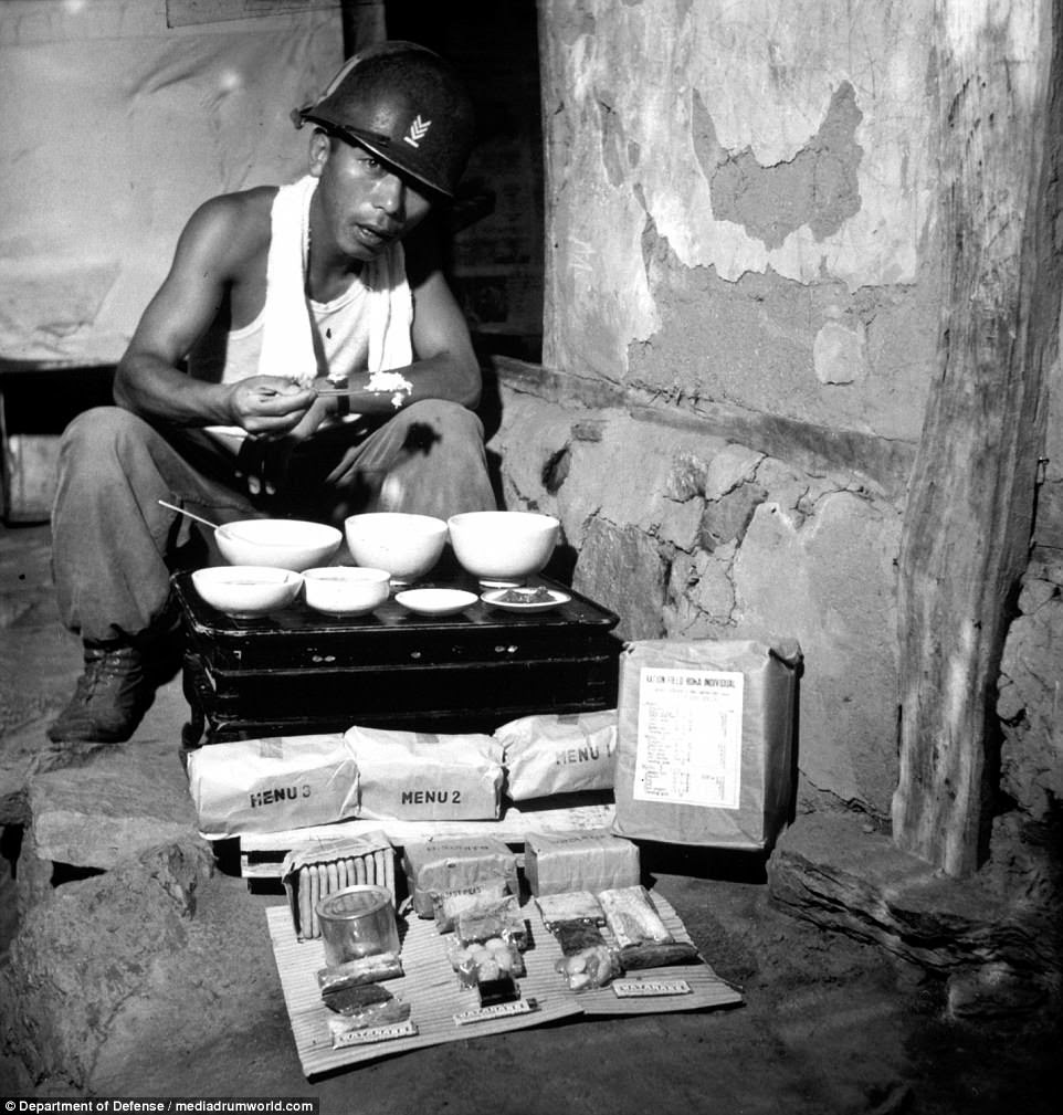 A soldier from the ROK Army eating lunch in a war-destroyed house in Munsan-ni, Korea, as a field ration made in Japan for the ROK Army is shown unpacked in July 1951