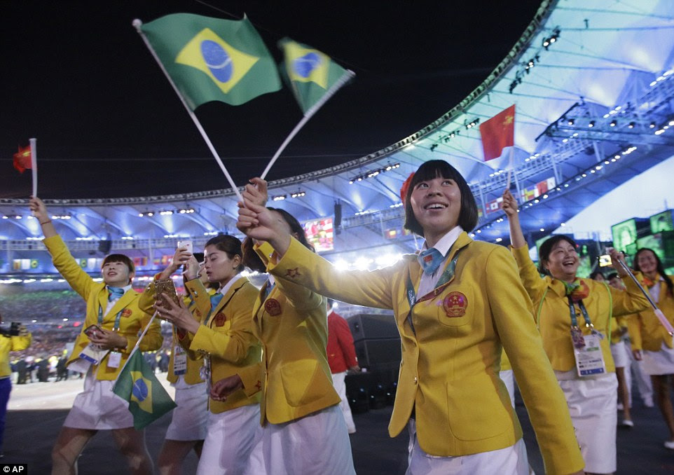 Equipe China caminha na arena durante a cerimônia de abertura dos Jogos Olímpicos de 2016 no Rio de Janeiro acenando as bandeiras brasileiras e chinesas