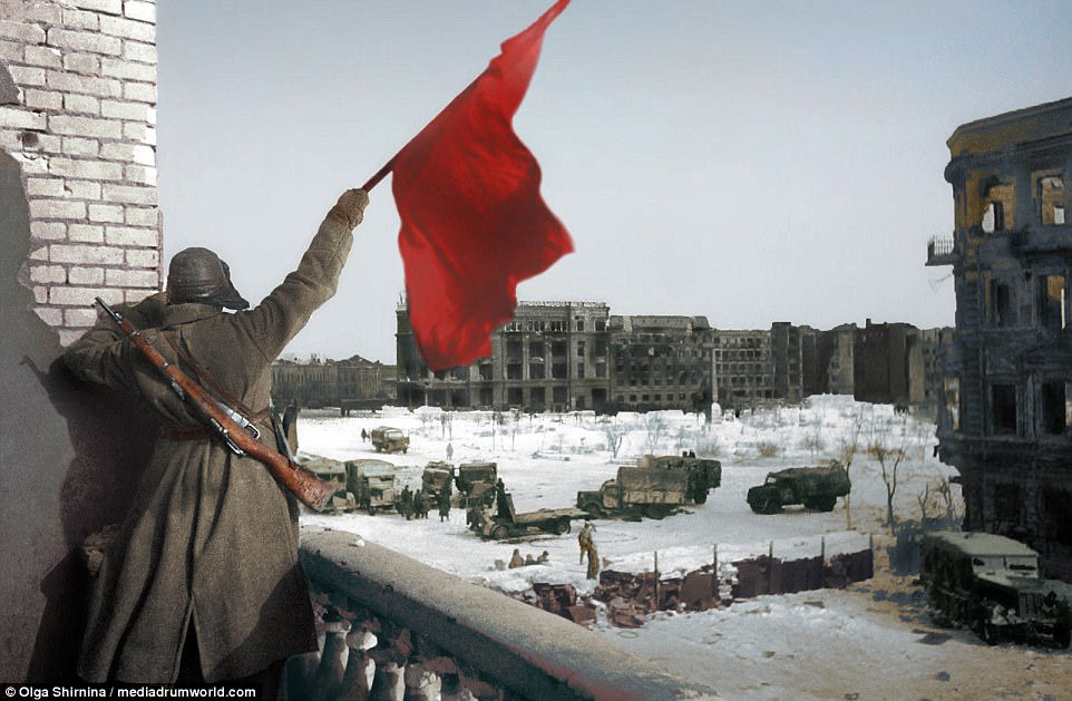 A Russian soldier waves a flag while standing on a balcony overlooking a square, where military trucks gather, during the Battle of Stalingrad, World War Two, Stalingrad (now Volgograd), USSR (now Russia). The soldier has a rifle strapped to his back. It has become one of the most iconic photographs of the bloody battle which claimed  