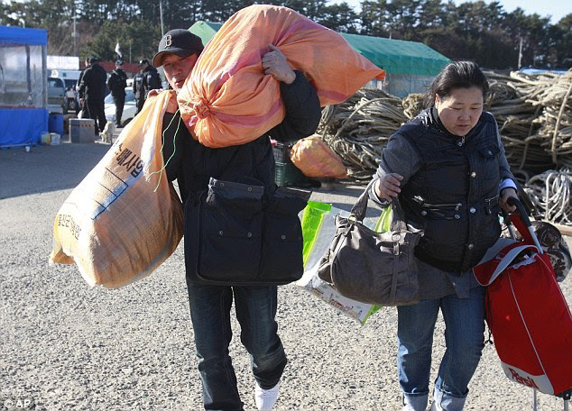 Escape: Residents carry their belongings as they try to get on a boat to leave the Yeonpyeong today
