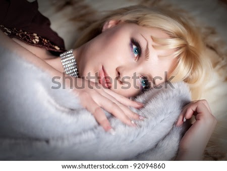 portrait of sexual blond woman dressed in fur and lingerie lying