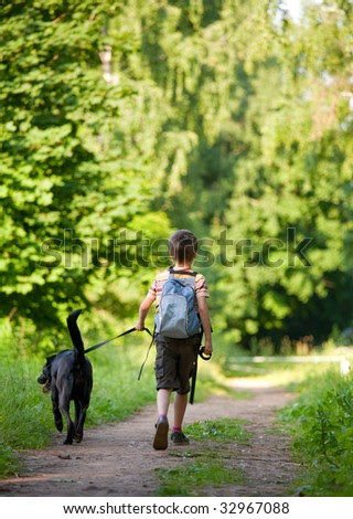 Young boy walking with black dog - stock photo