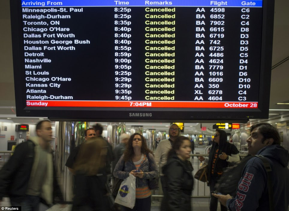 Stranded: Travellers surround a flight monitor showing cancelled flights at LaGuardia airport in New York last night