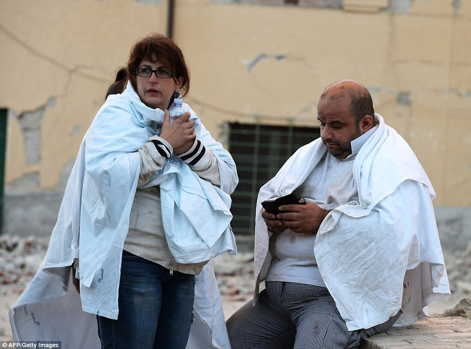 locals Truamatized tentar manter quente no início da manhã após o forte tremor sacudiu a cidade de Amatrice e grande parte da região central da Itália