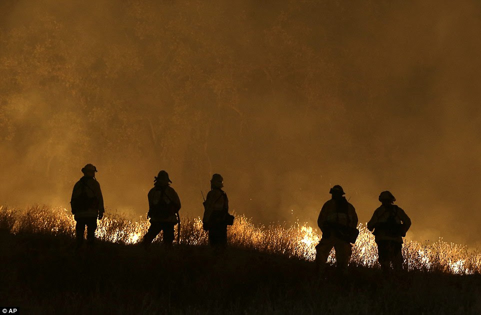 Firefighters stand guard as flames from the Butte Fire approach a containment line in San Andreas, California