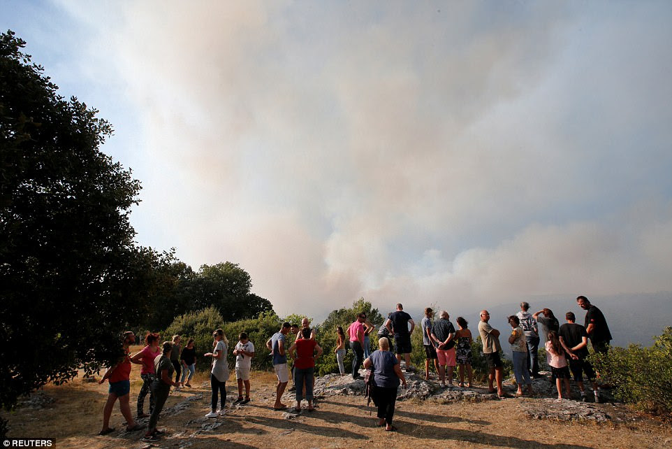 Holidaymakers watch on as the smoke fills the sky following a forest fire near Seillons, in the Var department in France