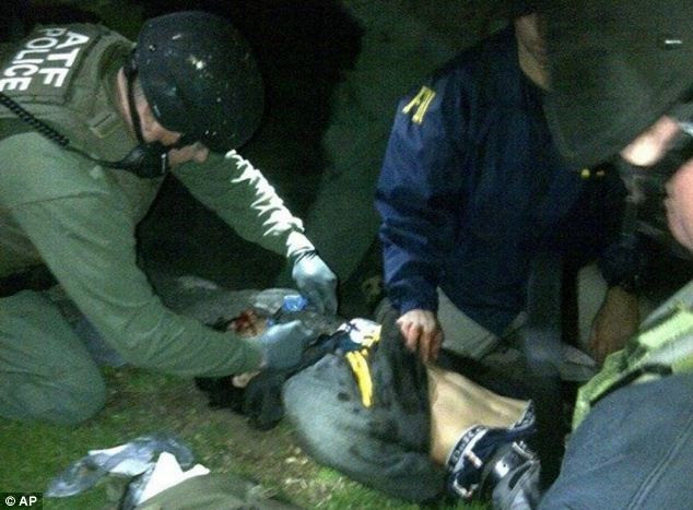 Apprehended: Dzhokhar is searched and given medical attention after he is found hiding on Friday evening
