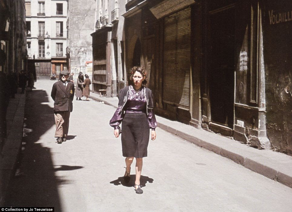 Real life under the Nazis: A woman walks a Parisian backstreet, in front of an older gentleman who is marked with the Star of David insignia that Jews were forced to wear