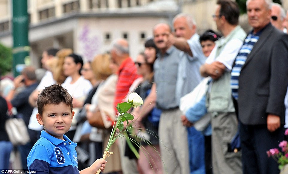 A boy holds flowers as Bosnians, citizens of Sarajevo, line up in the main street of Srebrenica to honour the victims of the Srebrenica 1995 massacre, as the remains of 175 victims are driven by truck to the Potocari memorial centre for a mass burial that will be held on July 11, on the 19th anniversary of Europe's worst atrocity since World War II.  "The remains of 175 massacre victims have been prepared for a joint funeral at the Potocari memorial centre" near the eastern town, a spokeswoman for Bosnia's Institute for Missing People told AFP on July 4. Around 8,000 men and boys died in the Srebrenica massacre which followed the town's seizure by Bosnia Serb forces on July 11, 1995. It was labelled a genocide by two international courts. So far, the remains of 6,066 people have had their remains exhumed from mass graves in the Srebrenica region for reburial in the Potocari cemetery. The massacre took place just a few months before the end of Bosnia's 1992-1995 war, which claimed some