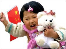 Child carrying Chinese flag and teddy bear