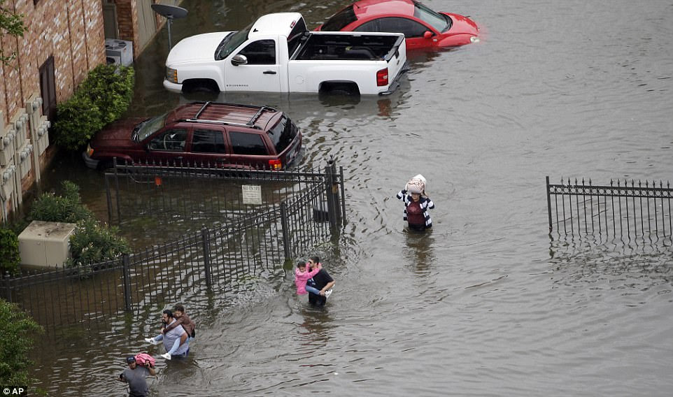 Residents carry children on their backs and hold their belongings above their heads on Tuesday as they flee their home near the Addicks reservoir which is on the verge of over spilling 