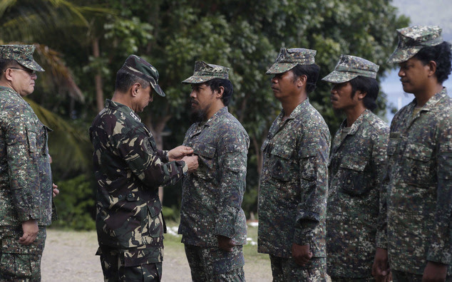 Philippine Western Command Chief Lt. Gen. Roy Deveraturda, pins a Bronze Cross medal on Marine 1st Lt. Mike Pelotera, Officer-in-Charge of a contingent which...