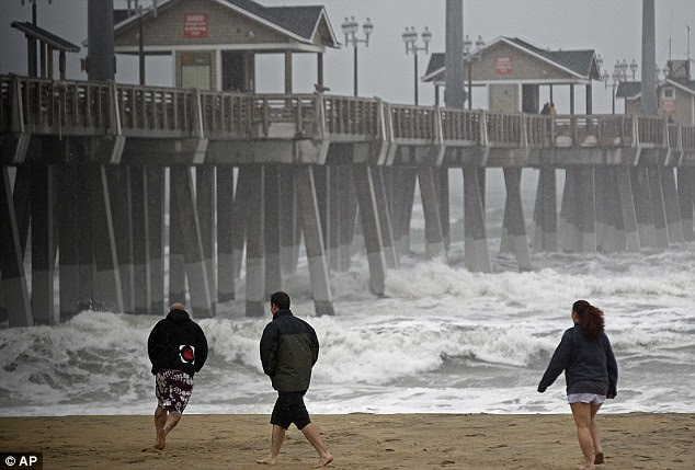 Wicked weather: Beachgoers walk in the wind and rain as waves generated by Hurricane Sandy crash into Jeanette's Pier in Nags Head, North Carolina
