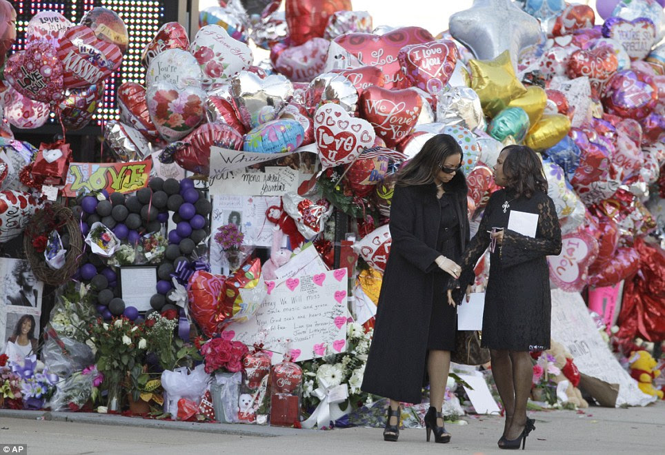 Vestida de preto: Duas mulheres uma pausa para olhar para o visor memorial antes de irem para a igreja para prestar suas últimas homenagens a Whitney Houston