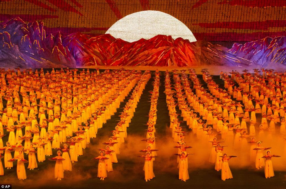 Red dawn: Thousands of dancers in Communist North Korea perform carefully choreographed routines while board holders create amazing backdrops in the stadium behind them